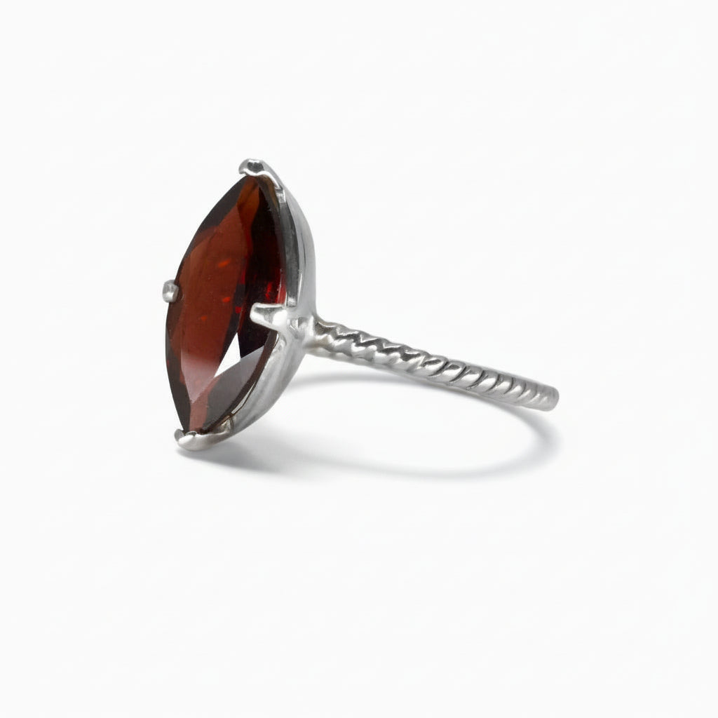 Marquise-cut deep red Garnet ring set in a polished sterling silver textured band on a white background.