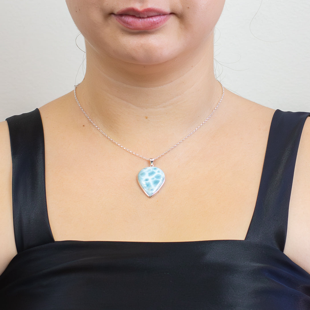 Teardrop Larimar pendant with soft blue and white wave-like patterns set in sterling silver on a chain. on model| MADE IN EARTH