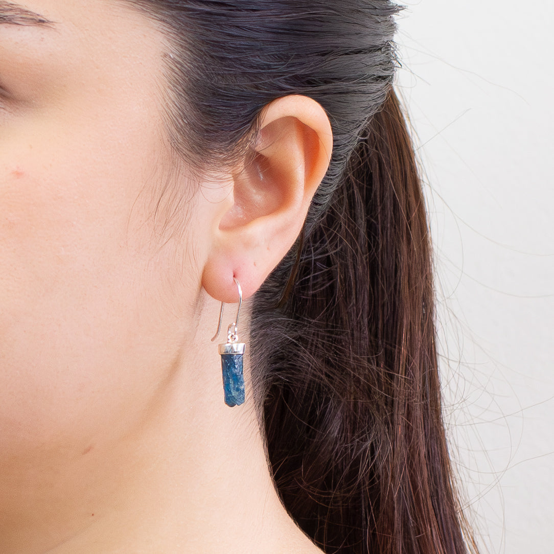 Raw Apatite crystal drop earrings in sterling silver featuring vibrant blue hexagonal stones on model. | MADE IN EARTH