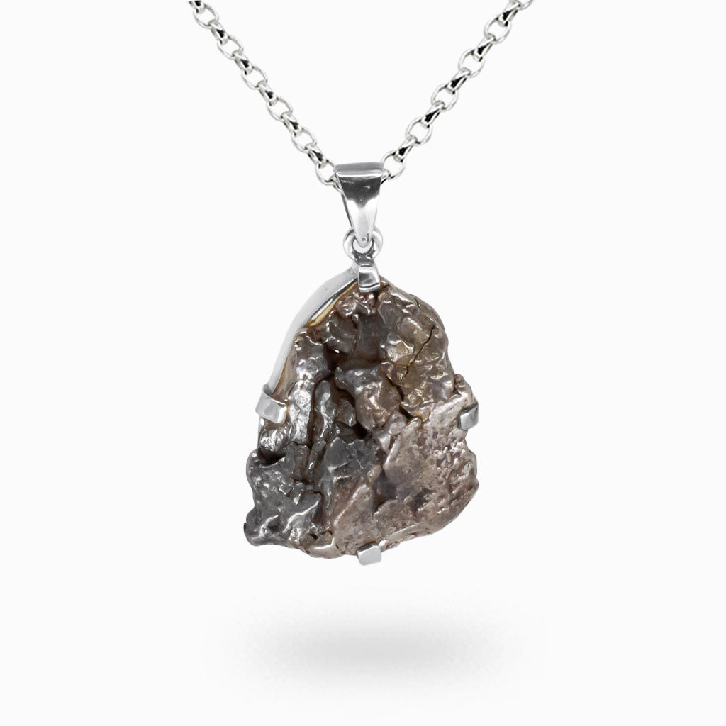 Raw Sikhote-Alin iron meteorite pendant with rugged metallic texture set in sterling silver prongs on a silver chain.