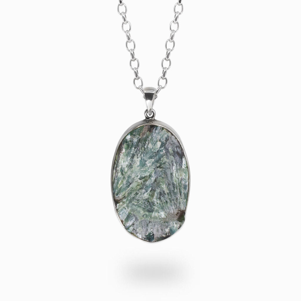 Oval green seraphinite gemstone pendant with feather-like patterns set in sterling silver bezel on chain.