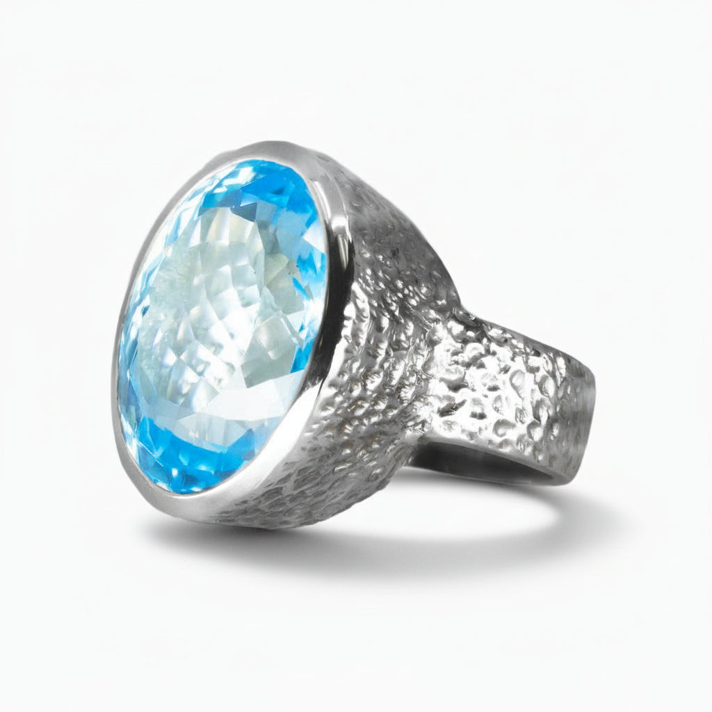Faceted oval Blue Topaz ring in sterling silver, featuring a bright electric blue gemstone against a white background | MADE IN EARTH