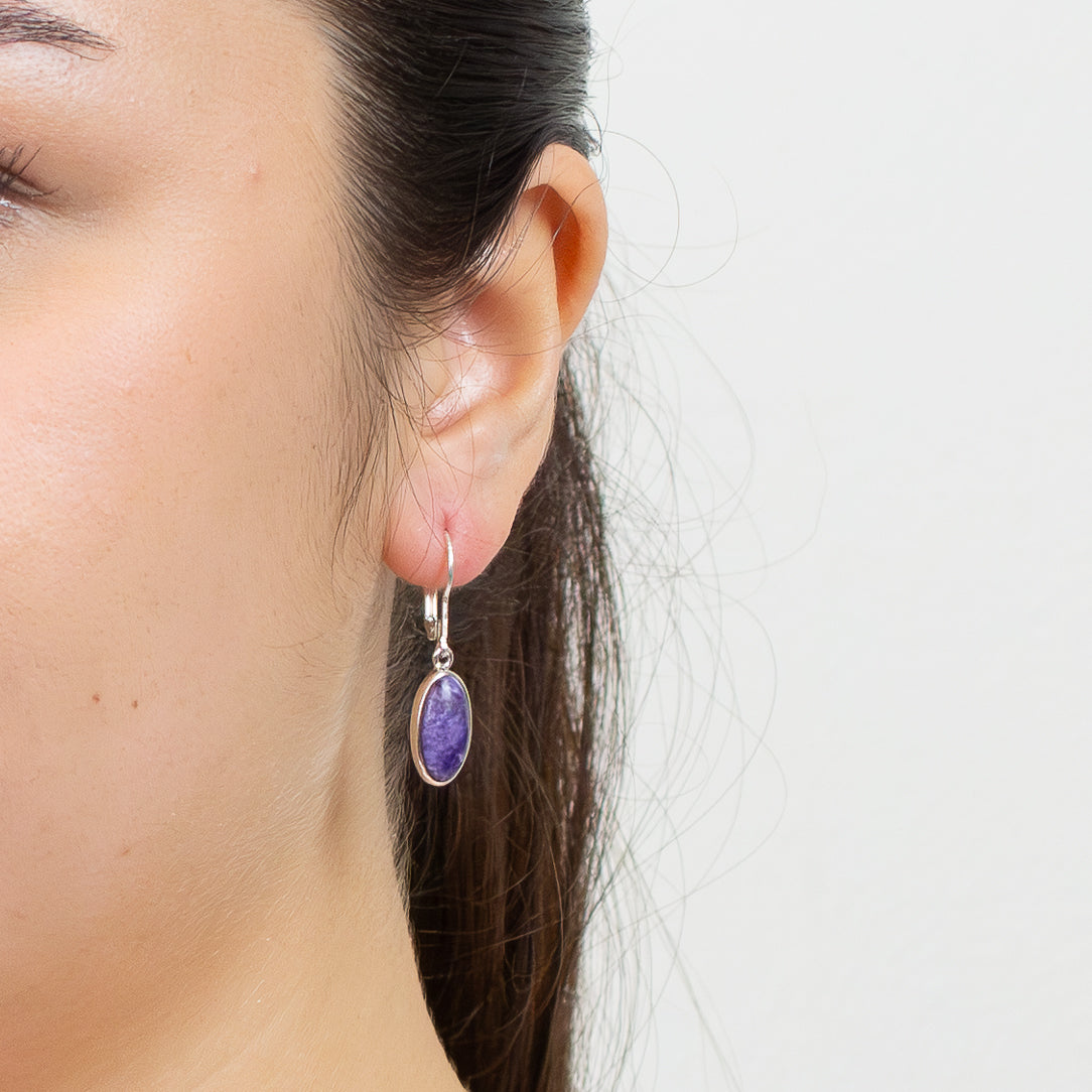 Sterling silver oval Charoite drop earrings with purple swirled cabochon stones and lever-back hooks ON MODEL. | MADE IN EARTH