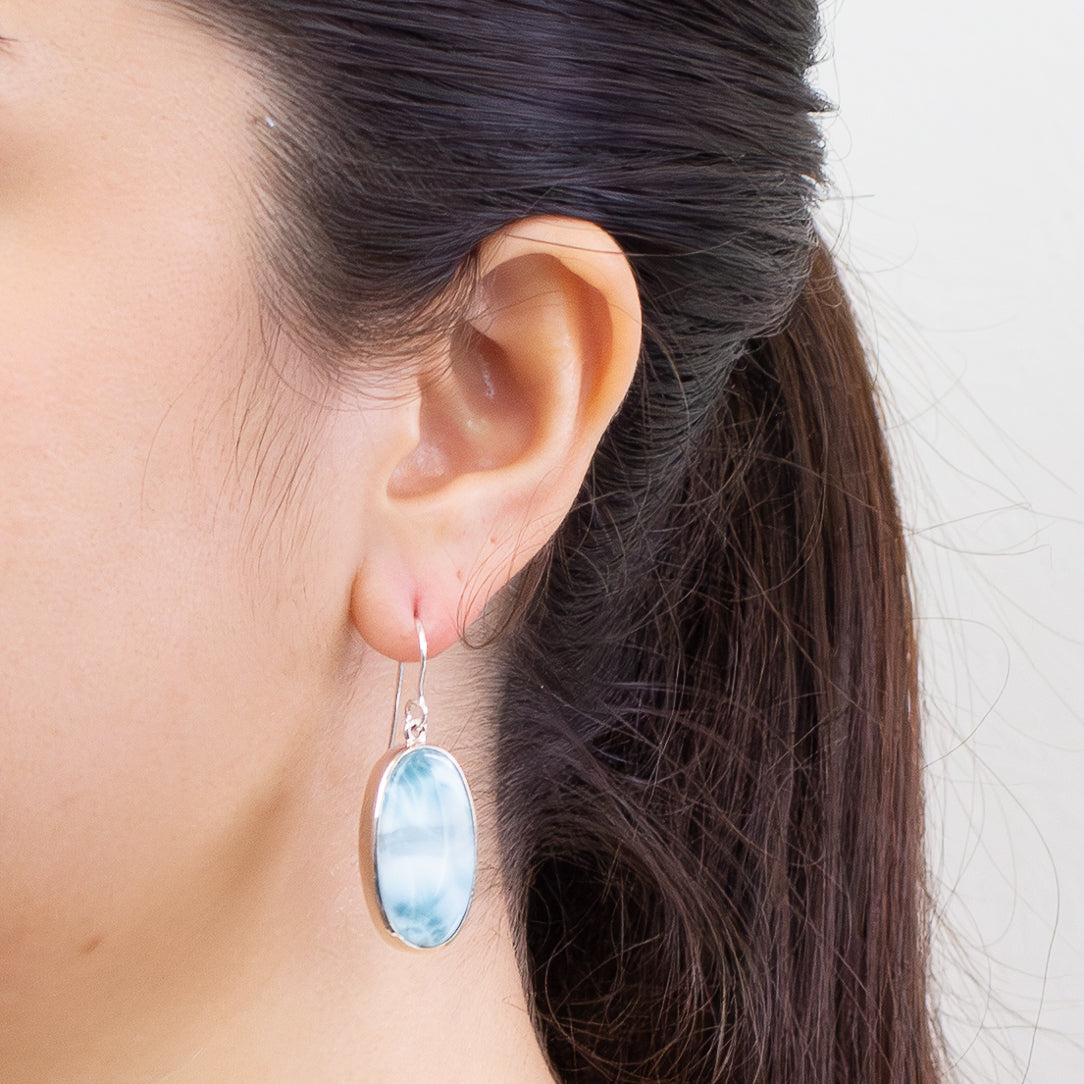 Oval Larimar gemstone drop earrings in sterling silver featuring soft ocean-blue patterns and a polished cabochon finish. | MADE IN EARTH