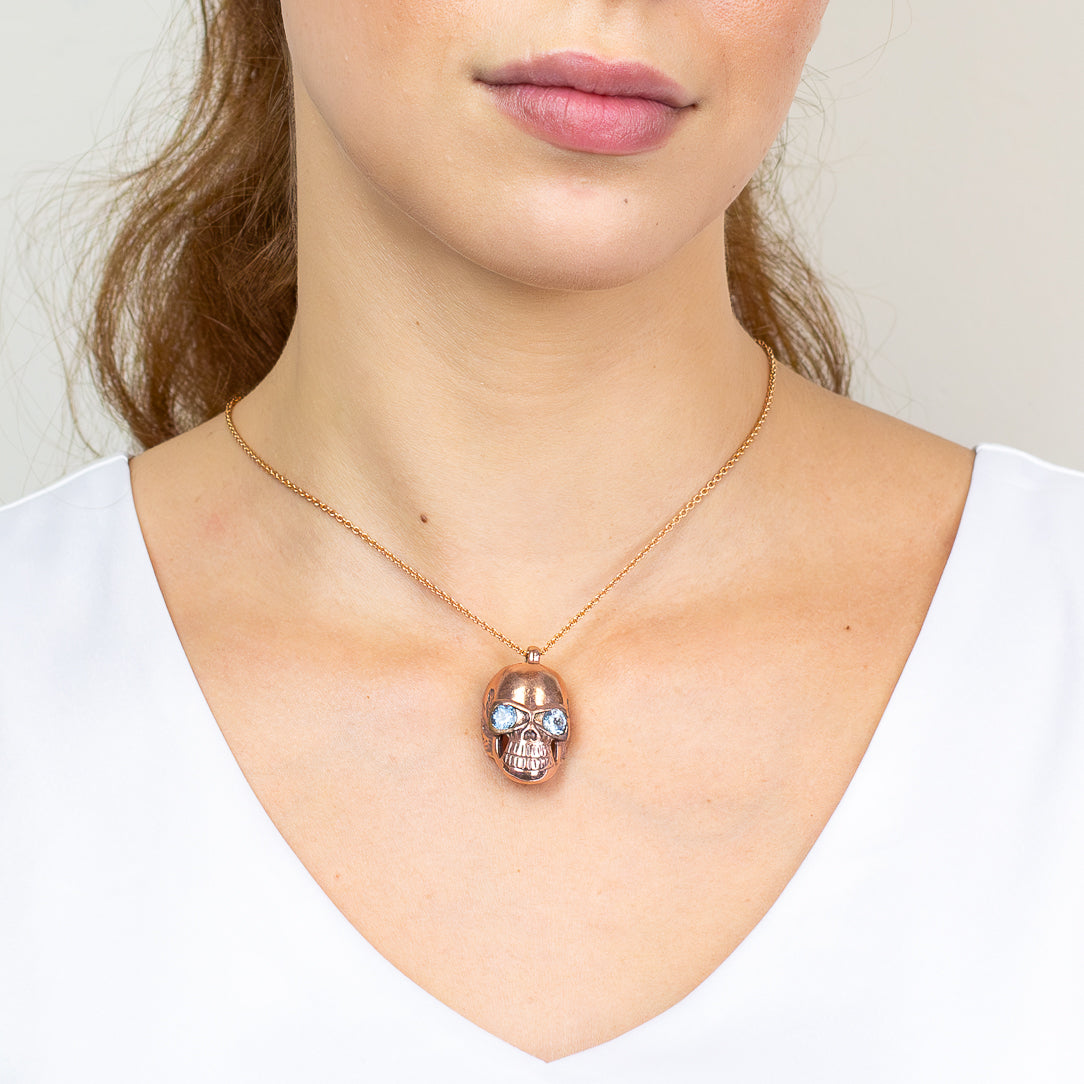 Rose gold skull pendant with blue topaz