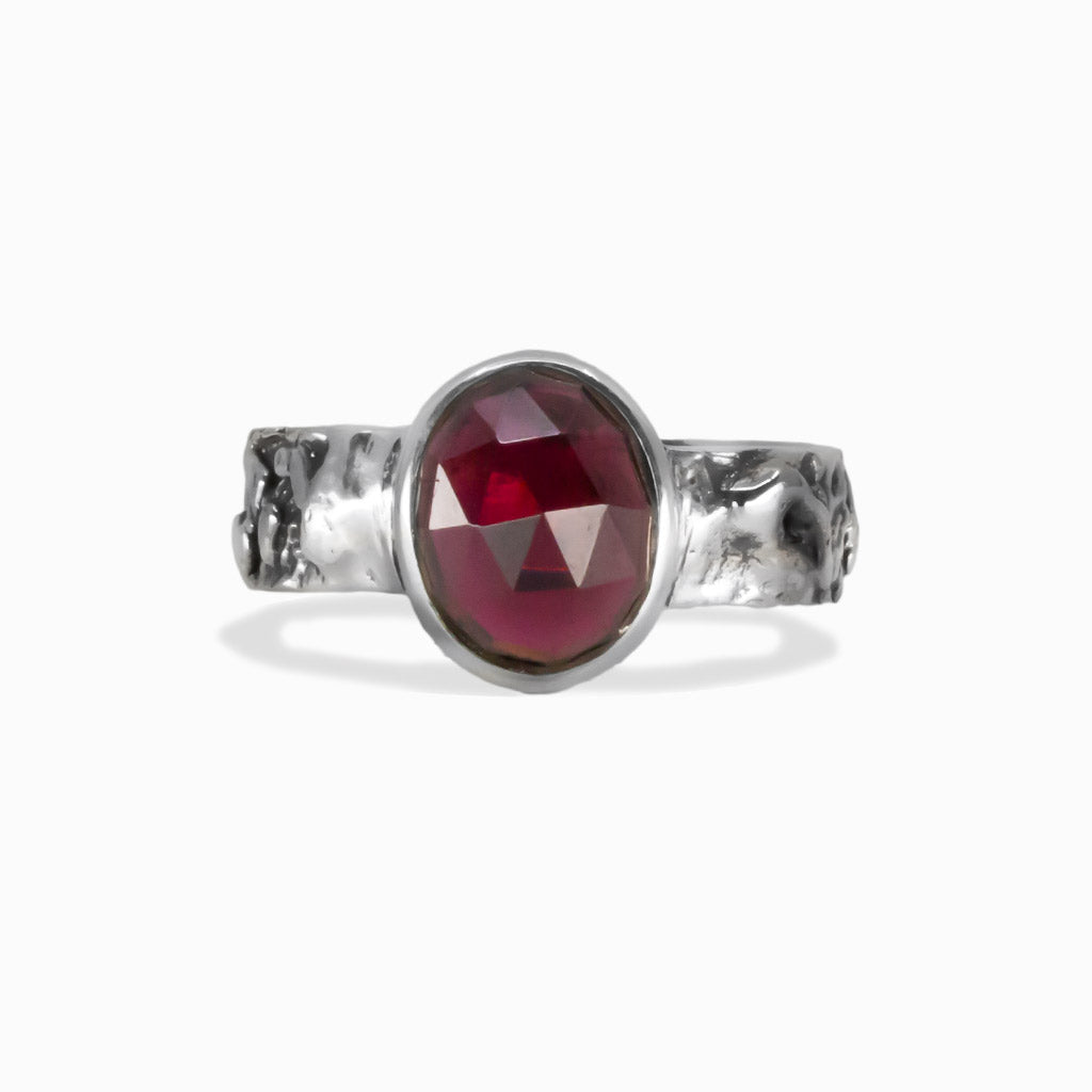 Garnet gemstone ring showing faceted oval stone set in textured silver band. | MADE IN EARTH