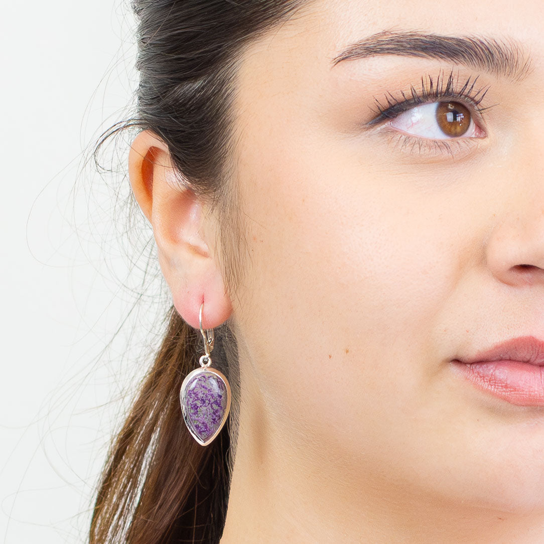 Close-up of a woman wearing a purple teardrop earring with a white background