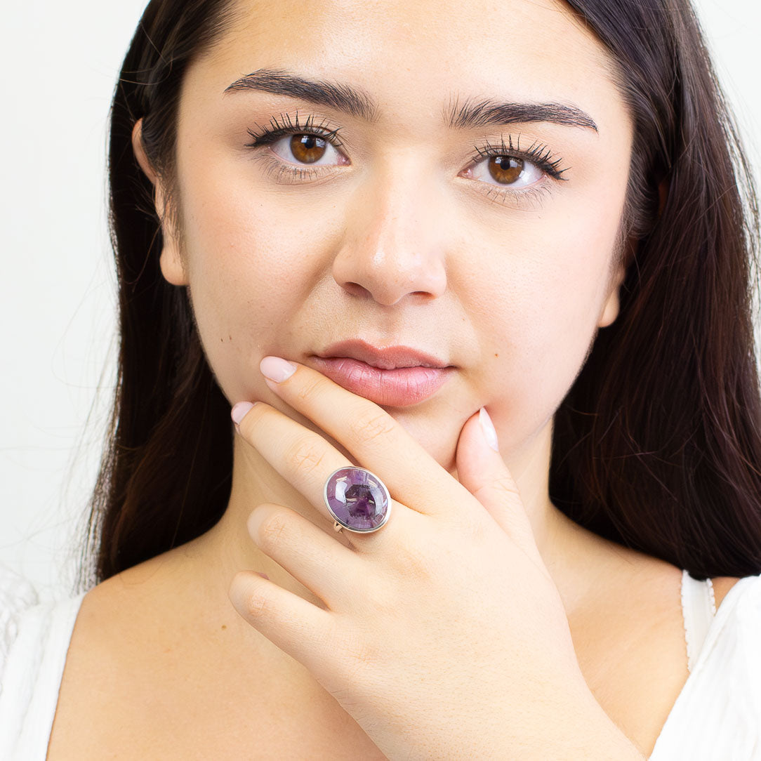 Oval Auralite 23 cabochon ring set in sterling silver bezel with purple mineral inclusions ON MODEL