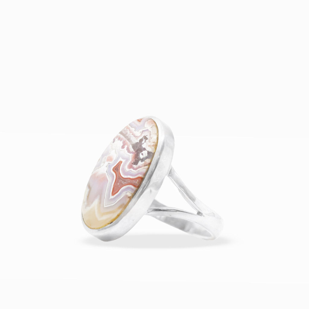 Oval Crazy Lace Agate ring with intricate cream, lavender, peach, and red banding in polished sterling silver bezel setting.