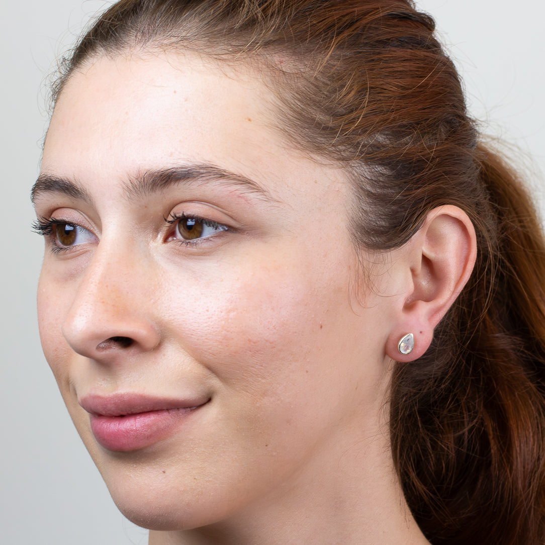 Close-up of a woman's face with a neutral expression, wearing a silver earring.