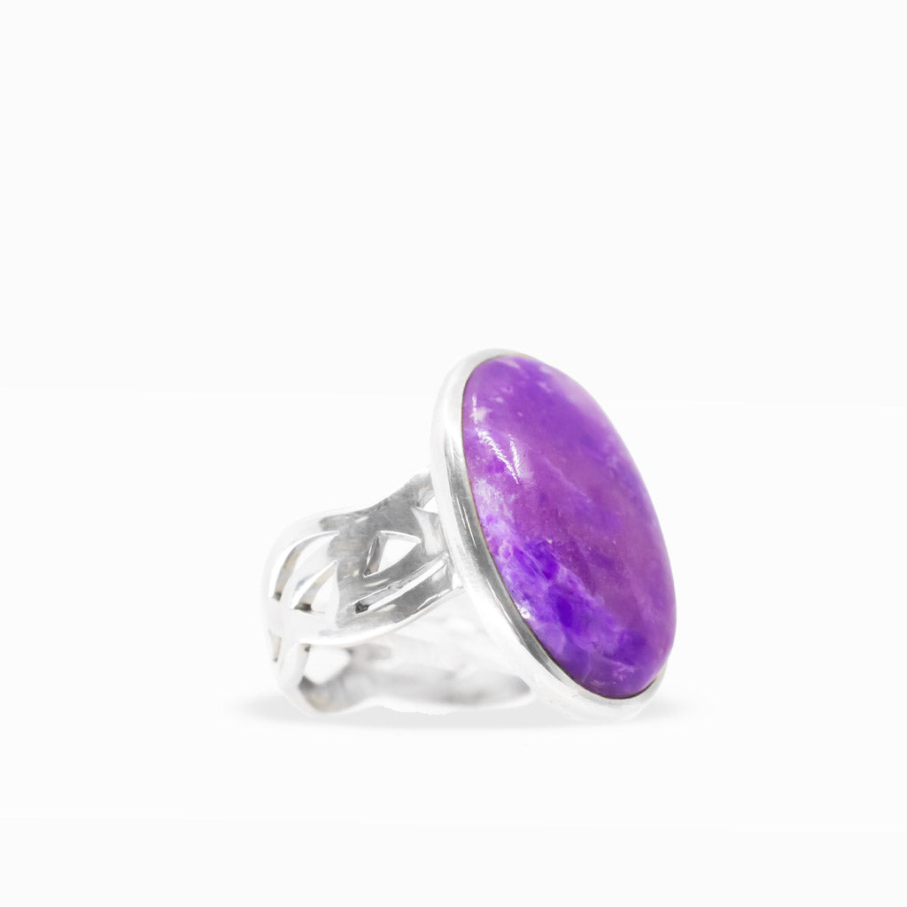 Large oval purple Sugilite ring with lavender marbling, polished sterling silver bezel setting, and decorative split band.