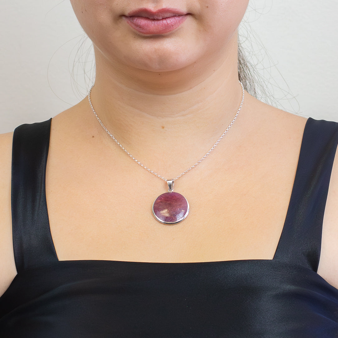 Round pink-red Ruby pendant set in sterling silver with vivid natural color variations.