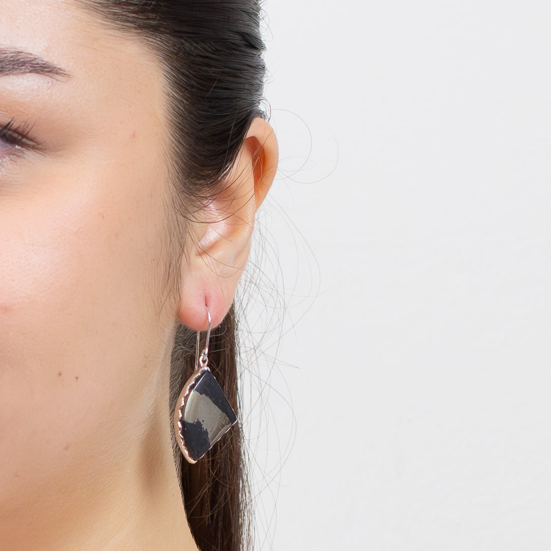 Apache Gold sterling silver earrings—black and gold cabochon drops offering grounding, clarity, and transformative, protective energy on model. | MADE IN EARTH