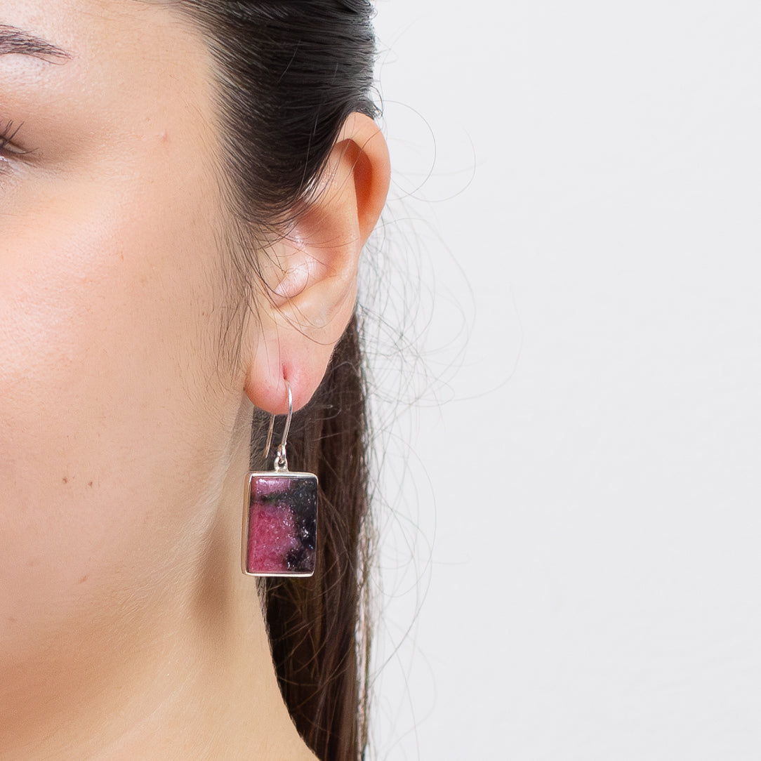 Rhodonite rectangular drop earrings in sterling silver with pink stone and black dendritic patterns on model. | MADE IN EARTH 