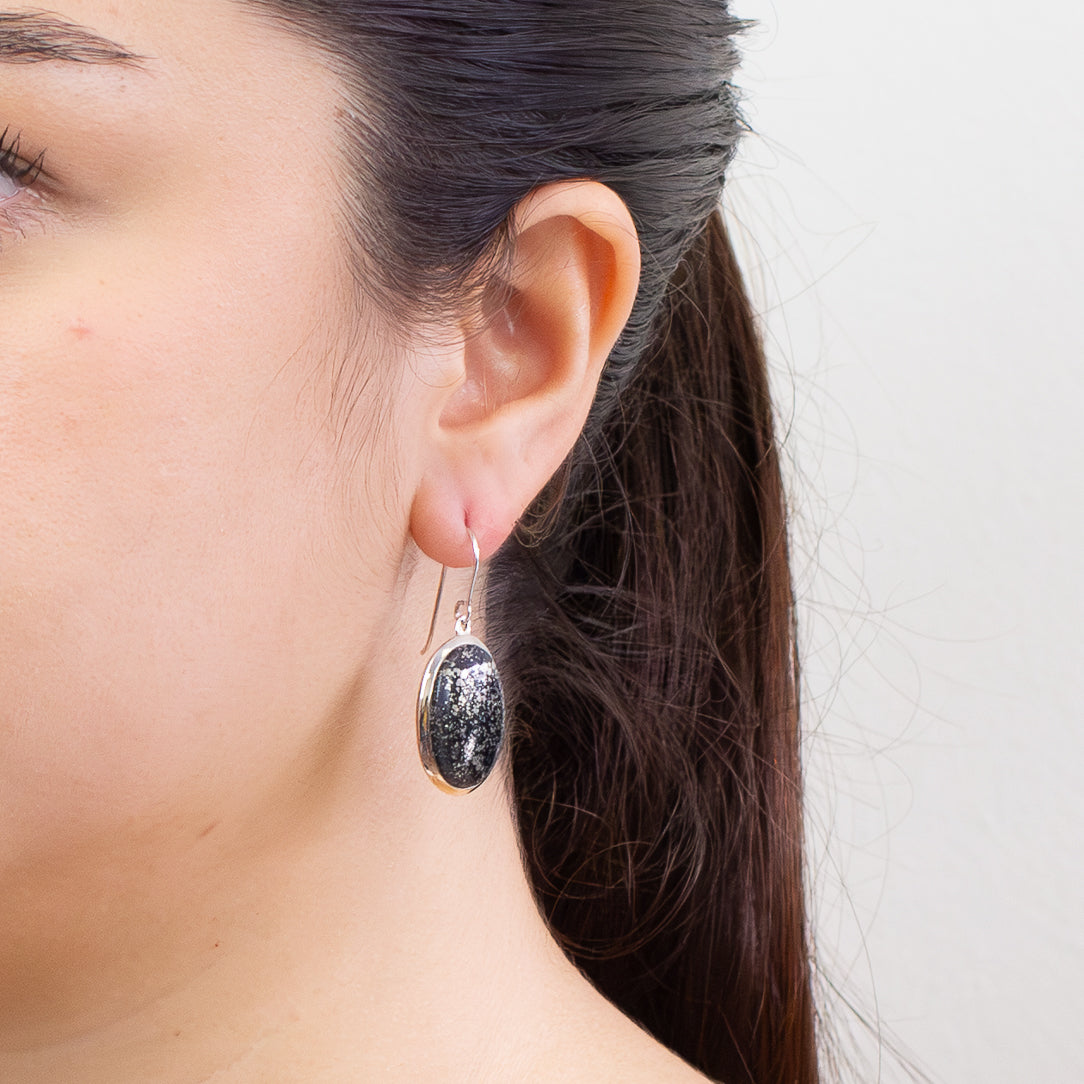 Swiss Pyrite oval cabochon earrings in sterling silver with black stone and gold flecks on model. | MADE IN EARTH