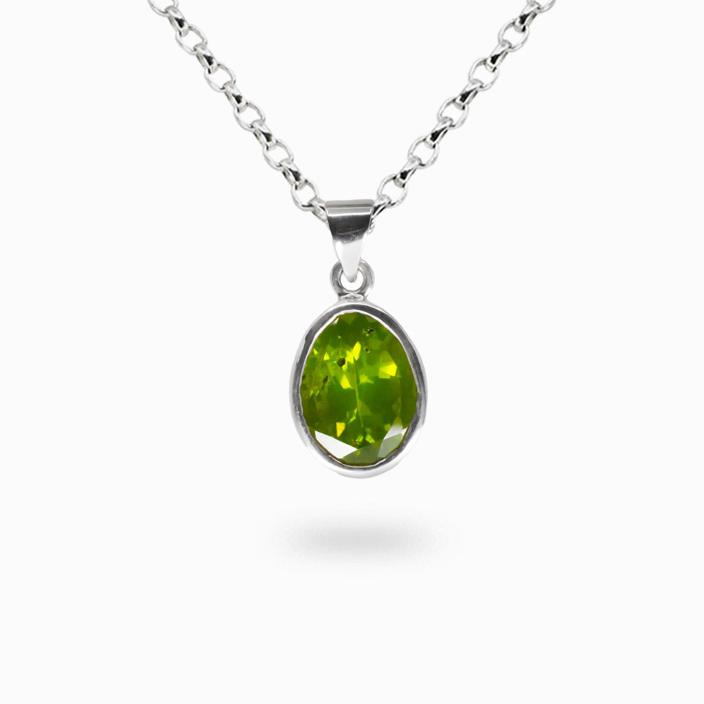 Faceted oval peridot gemstone pendant necklace set in sterling silver bezel on chain.
