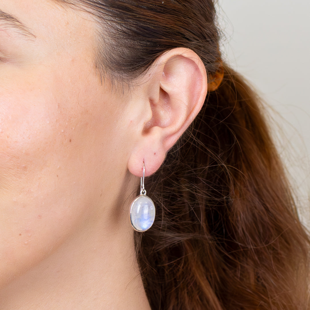 Sterling silver rainbow moonstone earrings featuring oval cabochon gemstones with soft blue iridescence.