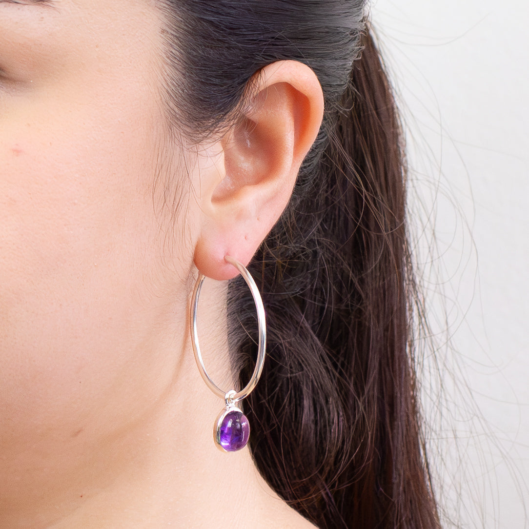 Oval amethyst cabochon hoop charms in sterling silver bezel attached to hoop earrings
