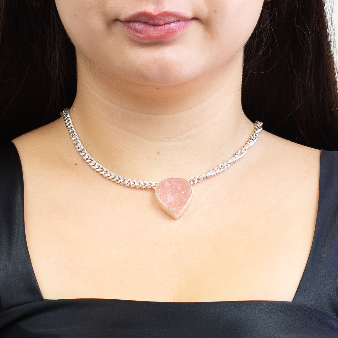 Raw teardrop rose quartz pendant with soft pink tones set in sterling silver with attached silver chain on model. | MADE IN EARTH