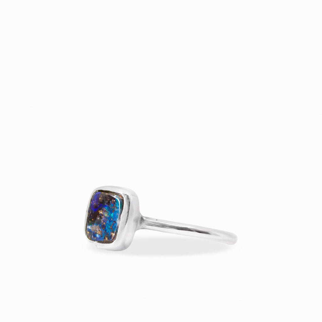 Rectangular Boulder Opal ring with electric blue and green flashes, natural brown ironstone matrix, and sterling silver bezel setting.
