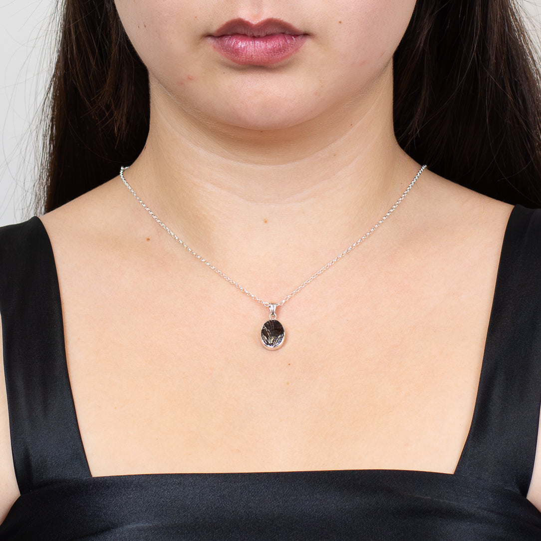 Raw oval shungite gemstone pendant set in sterling silver bezel necklace on model.