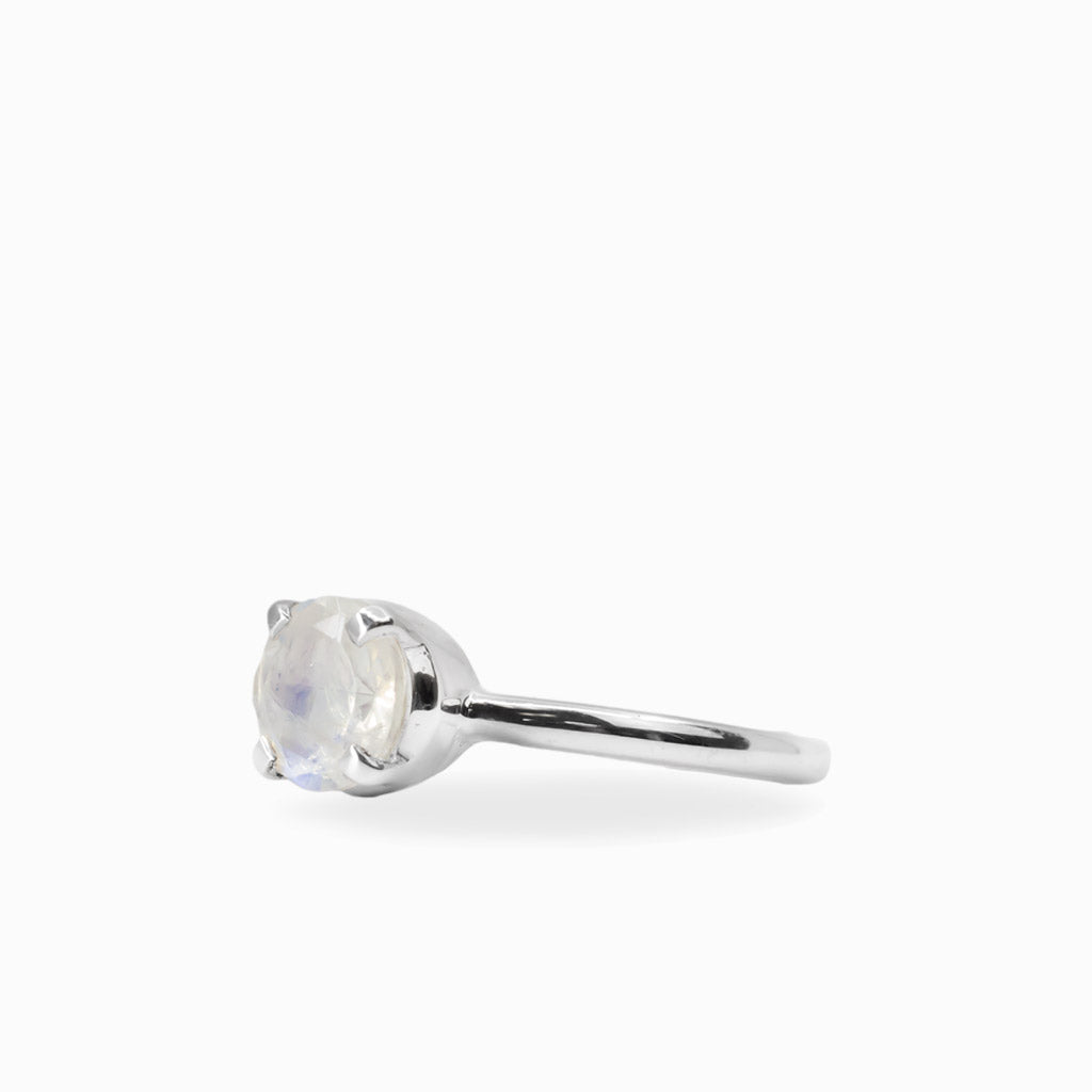Round faceted Rainbow Moonstone ring in polished 925 sterling silver with blue flashes, four-prong setting and slender band.
