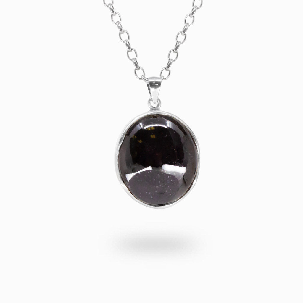 Round deep burgundy-purple Star Garnet cabochon pendant with a glossy polished surface in a 925 sterling silver bezel setting.