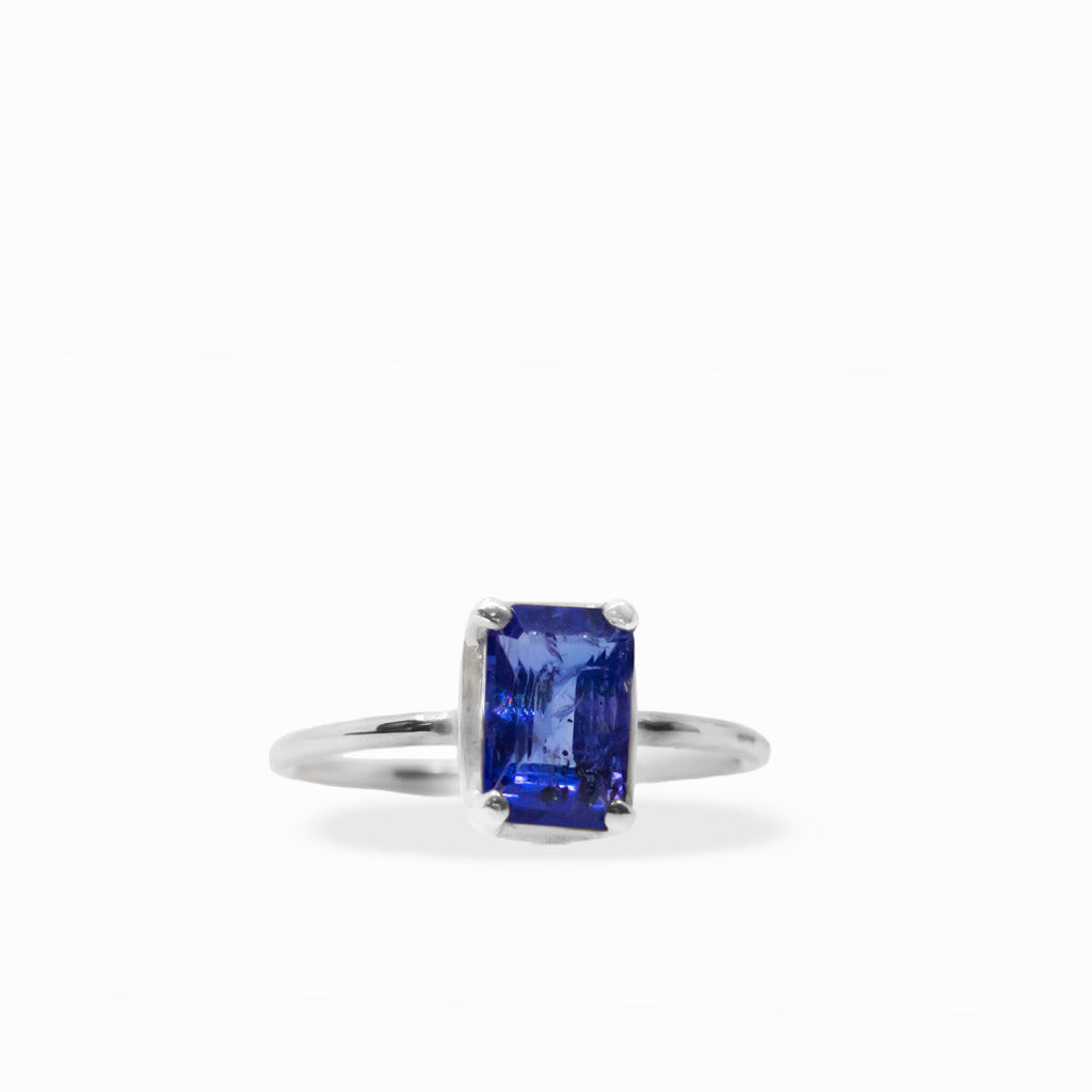 Vibrant violet-blue emerald-cut Tanzanite ring with four-prong sterling silver setting and polished slim band.