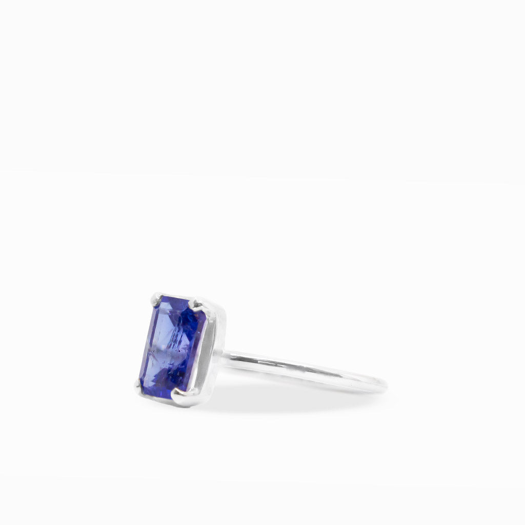 Vibrant violet-blue emerald-cut Tanzanite ring with four-prong sterling silver setting and polished slim band.
