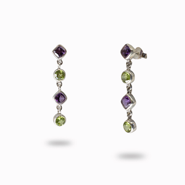 Pair of earrings with purple and green gemstones on a white background